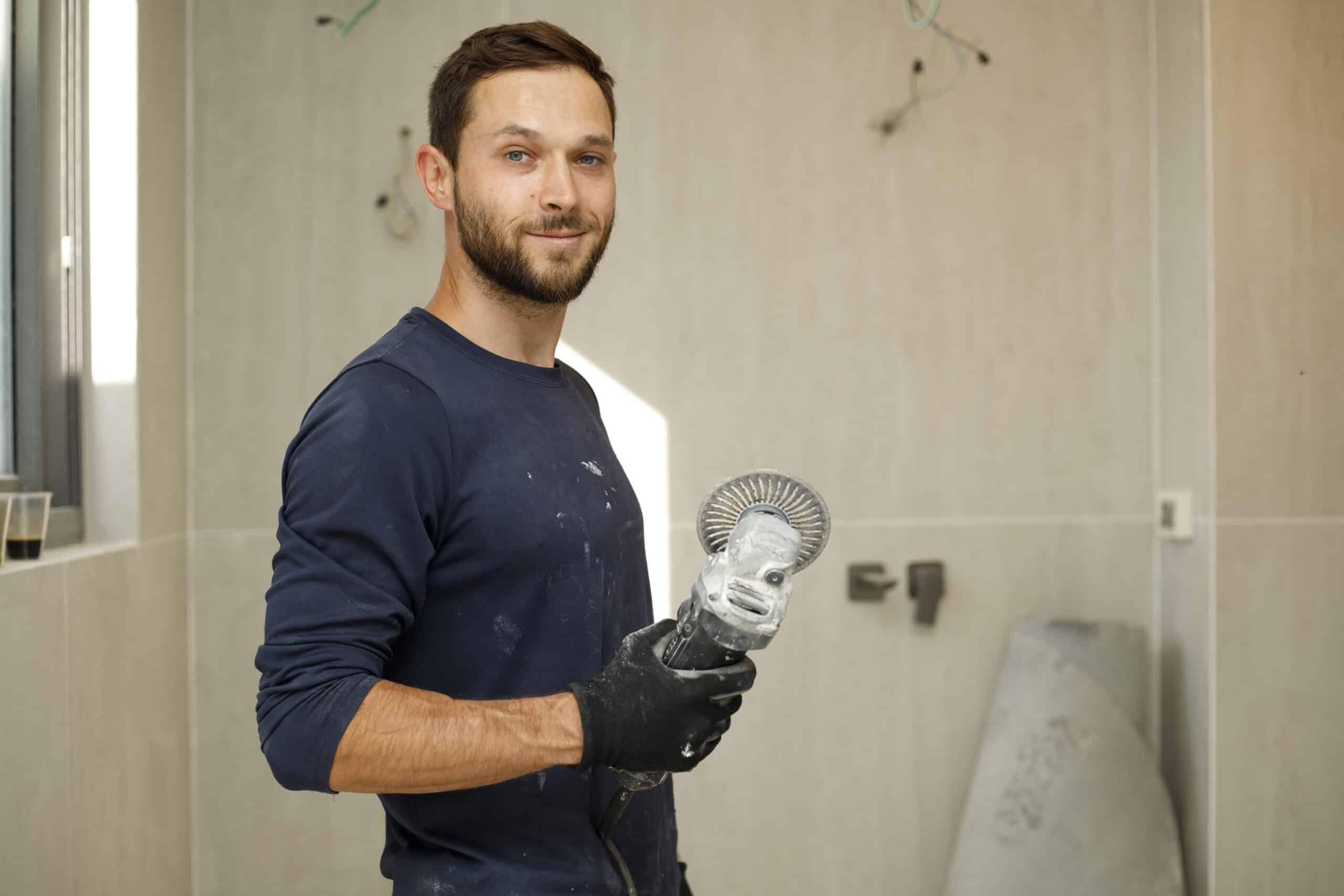 A worker uses an angle grinder while carrying out repair work.